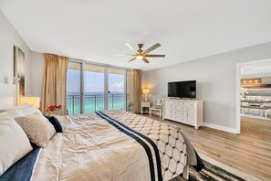 Ett hotellrum med en stor säng, en takfläkt, en tv och utsikt över havet.