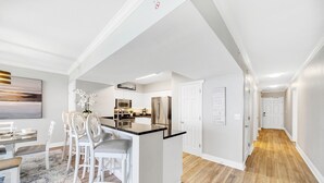 A modern kitchen with white cabinetry, a central island, and stainless steel appliances.