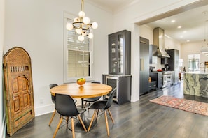 A modern kitchen with dark cabinetry, a central island, and a dining area with a round table and chairs.