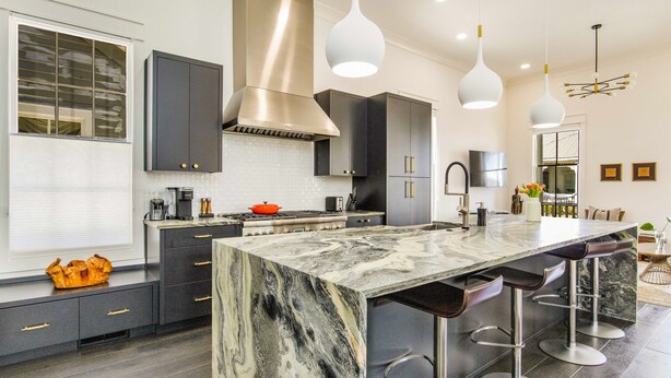 A modern kitchen with a large island, dark cabinets, and pendant lighting. - Downtown Pensacola Historic Home (pensacola)