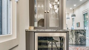 A modern kitchen with a marble countertop, a built-in wine fridge, and a glass door cabinet. - Downtown Pensacola Historic Home (pensacola)