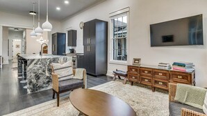 A modern kitchen with dark cabinets, a marble island, and pendant lighting. - Downtown Pensacola Historic Home (pensacola)