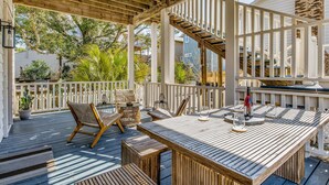 A wooden deck with outdoor furniture, including a table and chairs, and a staircase leading to an upper level. - Downtown Pensacola Historic Home (pensacola)