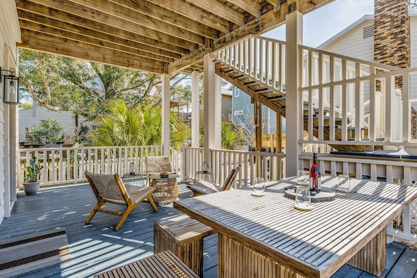 A wooden deck with outdoor furniture, including a table and chairs, and a staircase leading to an upper level.