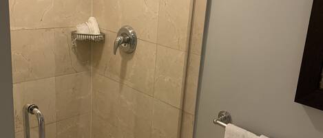 A walk-in shower with a glass door, a towel rack, and a showerhead.