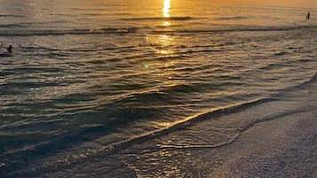A beach scene with the sun reflecting on the water.