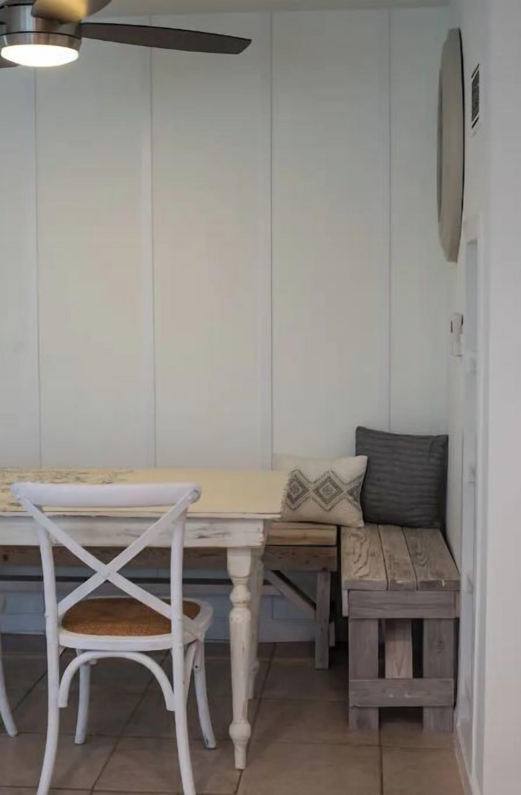 A dining area with a white table, a wooden bench, and a white chair.