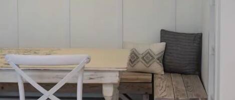 A dining area with a white table, a wooden bench, and a white chair.