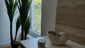 Habitación moderna con encimera blanca, planta en maceta, vela y vista a zonas verdes.
