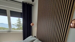 Un dormitorio con cama, ventana con vistas, cabecero de madera y mesita de noche.