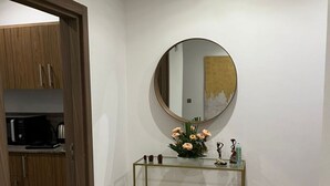 Un baño moderno con un espejo redondo, una mesita consola de vidrio y un armario de madera.
