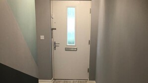 Ein Flur mit einer Tür, einem Fenster und einer Heizung.