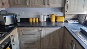 Eine Küche mit Holzausstattung, einer Mikrowelle, einem Toaster und gelben Behältern auf der Arbeitsplatte.