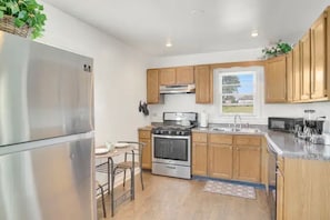Una cocina moderna con armarios de madera, electrodomésticos de acero inoxidable y un ventanal que proporciona luz natural.