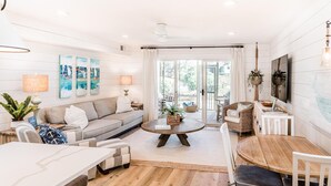 A spacious living room with a sofa, coffee table, dining table, and chairs.