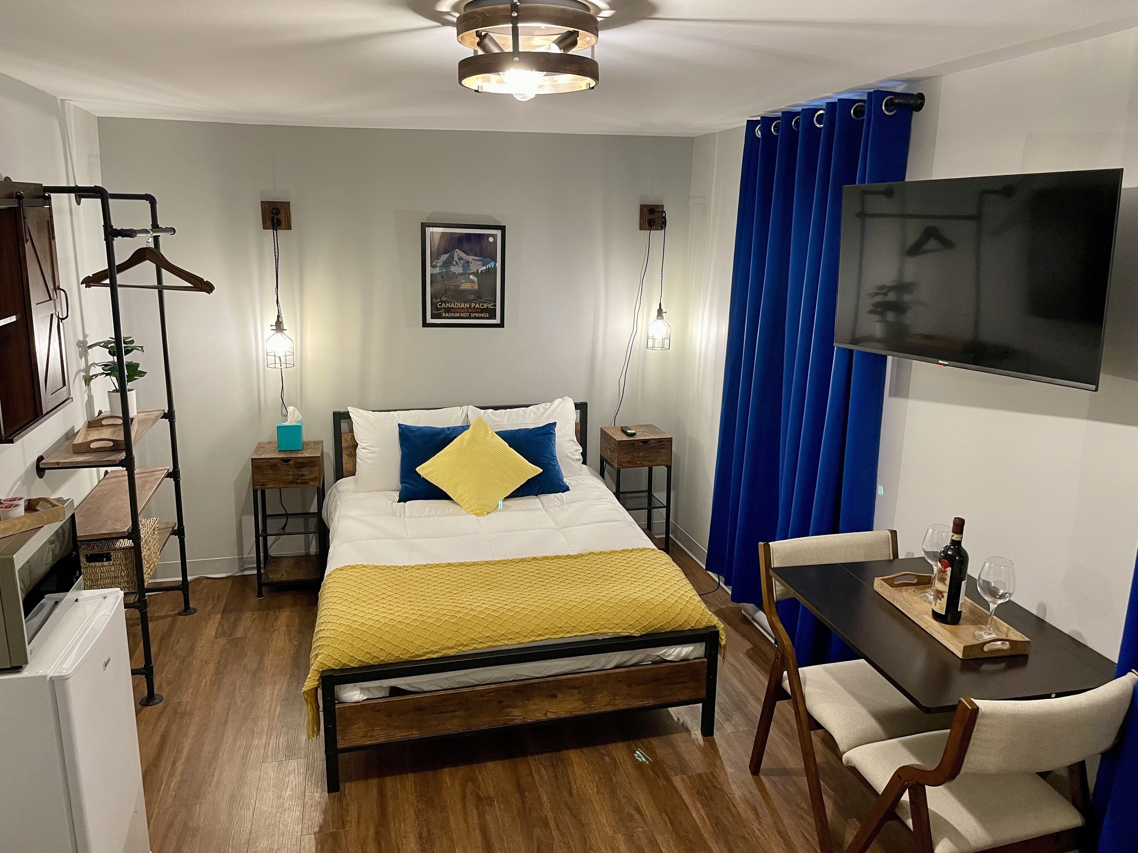 Habitación de hotel con cama, mesitas de noche, escritorio con silla, televisión y armario.