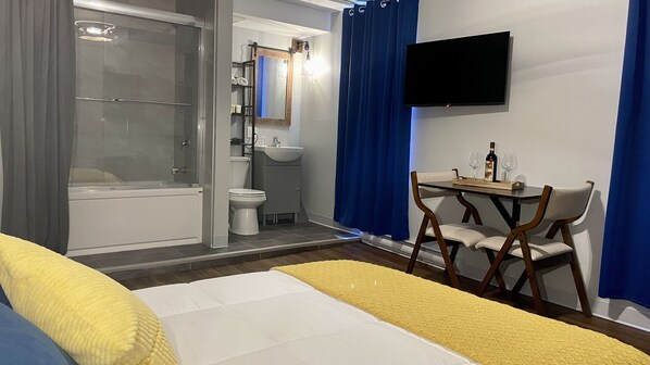 A modern hotel room with a bed, a desk with two chairs, a TV, a shower, and a toilet. - Grand Central Hotel Richmond (Richmond)