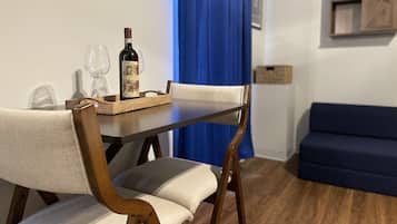 A dining area with a wooden table, two chairs, a wine bottle, and glasses.