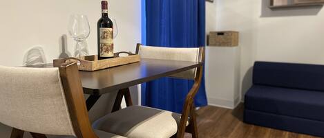 Un comedor con mesa de madera, dos sillas, una botella de vino y copas.
