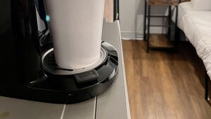 A coffee machine dispensing coffee into a cup, a bedside table, a lamp, and a bed in a hotel room. - Grand Central Hotel Richmond (Richmond)