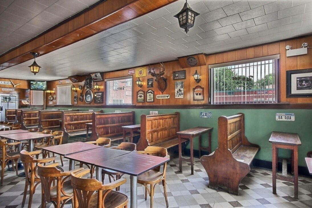 Un restaurant avec des banquettes et des tables en bois, un sol à carreaux et diverses décorations murales, notamment des horloges et des tableaux encadrés.