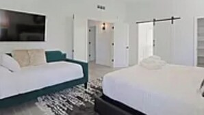 Ein modernes Schlafzimmer mit einem Bett, einer Couch, einem Deckenventilator und einem Fernseher.