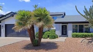 Ein modernes, zweigeschossiges Haus mit Garage, gepflegtem Rasen und einer Palme im Vorgarten.
