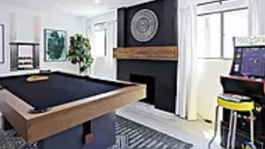 Ein modernes Wohnzimmer mit Billardtisch, Kamin und einer Spielecke.