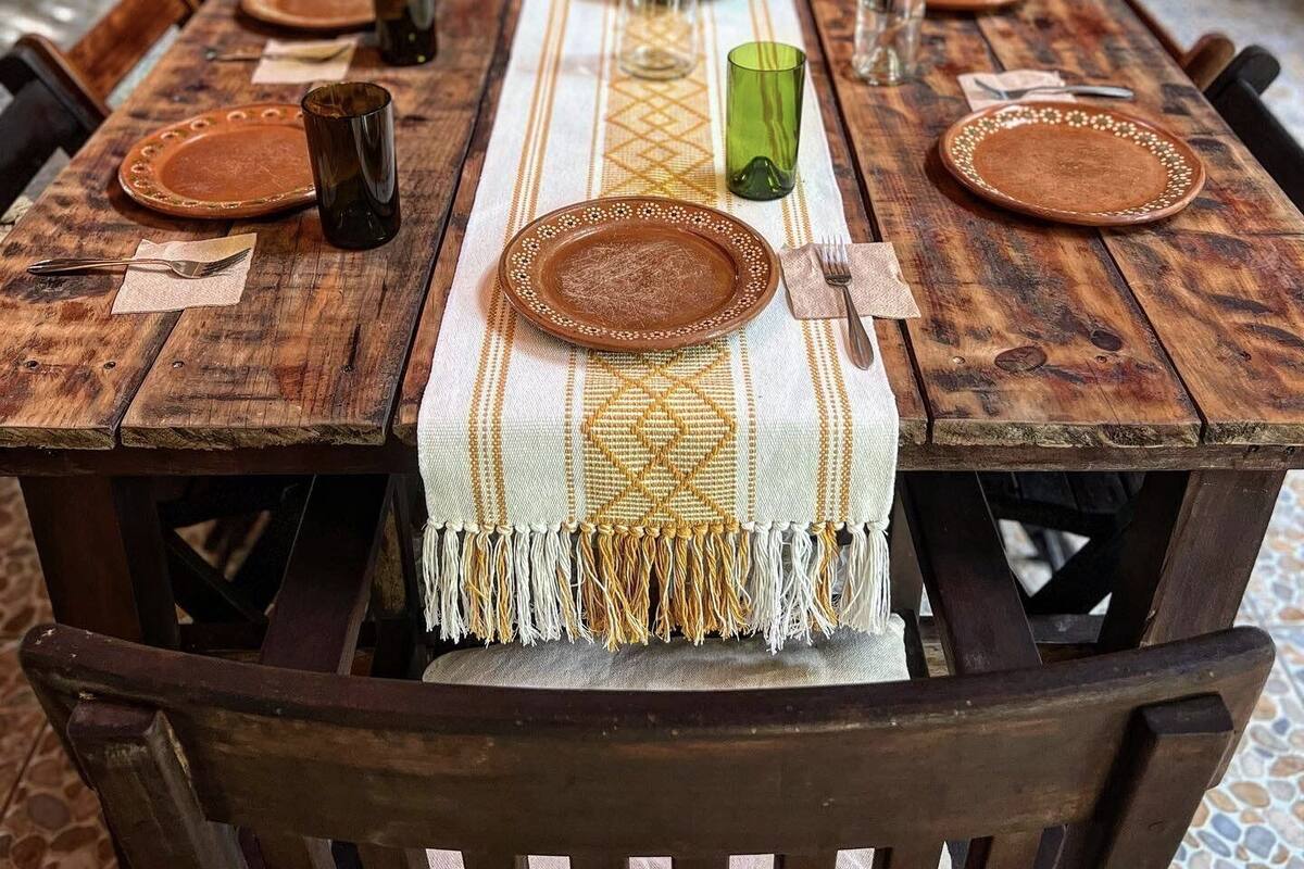 A wooden dining table with a woven placemat, surrounded by chairs.