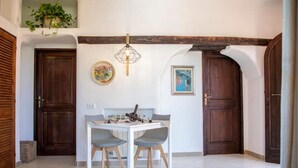 Zona pranzo con tavolo bianco e due sedie, un lampadario e due porte in legno.