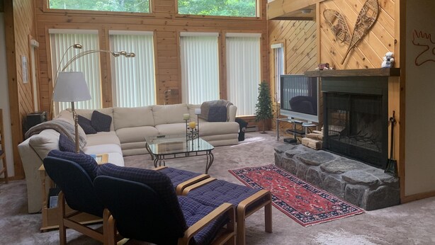 Un salon chaleureux avec une cheminée, des murs en bois et de grandes fenêtres.