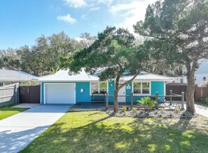 Ein eingeschossiges Haus mit Garage, einem kleinen Vorgarten mit Baum und blauem Himmel.