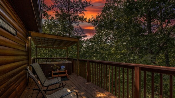 A wooden deck with a covered seating area and a hot tub. - Hot Tub, Game Room, Pool Table, Fireplace | Minutes to Pigeon Forge (Sevierville)