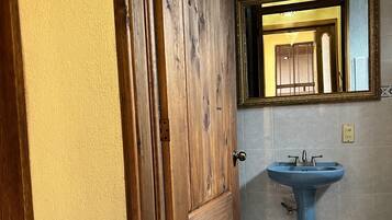 A bathroom with a wooden door, a blue sink, and a tiled floor.