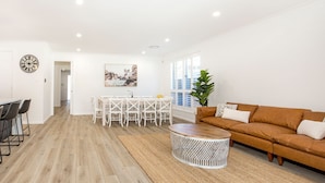 Un vaste espace de vie doté d’un plancher en bois, d’une table basse ronde, d’un canapé marron et d’une table à manger avec des chaises.