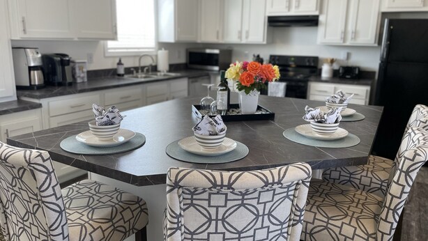 Una cocina moderna con armarios blancos, una isla central y sillas con estampado.