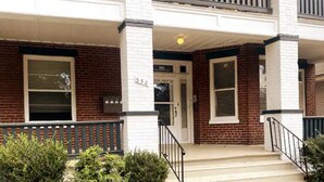 A two-story building with a brick facade, white trim, and a front porch with steps and railings. - Highland Park Place: Historic Two Bedroom Apt! (Roanoke)