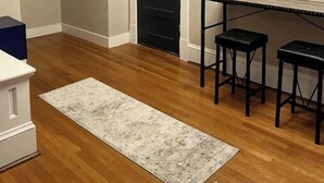 A room with wooden flooring, a white door, a painting on the wall, and a small table with two stools. - Highland Park Place: Historic Two Bedroom Apt! (Roanoke)