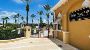 En port giver adgang til et marked med skilt, der viser "The Marketplace at Regal Palms", hvor du kan købe dagligvarer, gaver og badetøj.