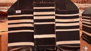 A tent-like structure with a bench in front, set against a desert landscape with rock formations. - Khaleds Camp (Wadi Rum)