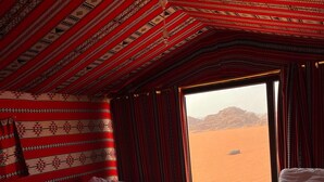 A room with two beds, a small table, and a view of a desert landscape. - Khaleds Camp (Wadi Rum)