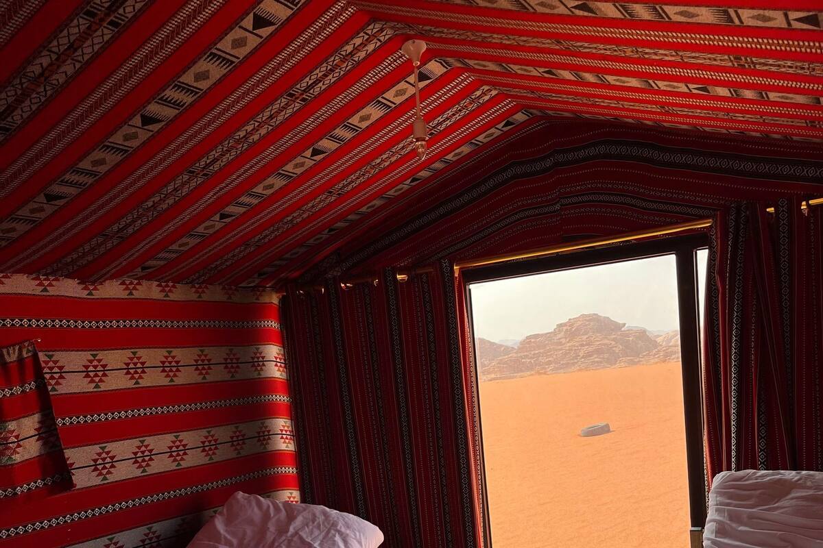 Une chambre avec deux lits, une petite table et une vue sur un paysage désertique.