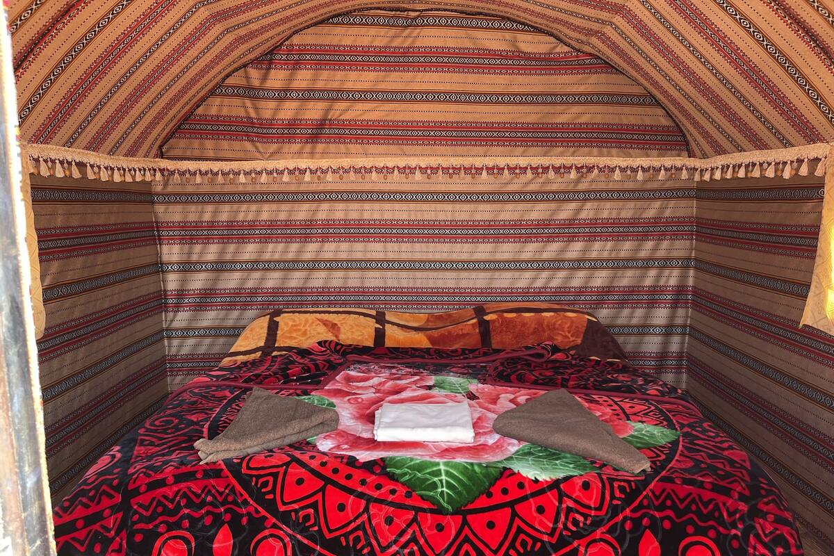 Une chambre avec un lit recouvert d’une literie à motifs, un oreiller et une couverture.