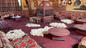A traditional room with patterned textiles, a central fireplace, and multiple seating areas. - Khaleds Camp (Wadi Rum)
