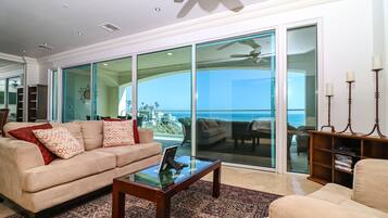 Un vaste salon doté d’une grande porte vitrée donnant sur un balcon avec vue sur l’océan.