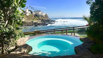 Una piscina con vista al océano y un edificio al borde de un acantilado.