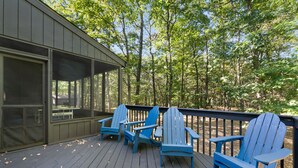 A wooden deck with blue Adirondack chairs and a covered area with a table and chairs. - Modern Poconos Game House! Hot Tub, Fire Pit (East Stroudsburg)