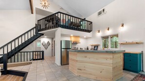 A spacious kitchen with a central island, a staircase leading to an upper level, and a view of the outdoors. - Modern Poconos Game House! Hot Tub, Fire Pit (East Stroudsburg)