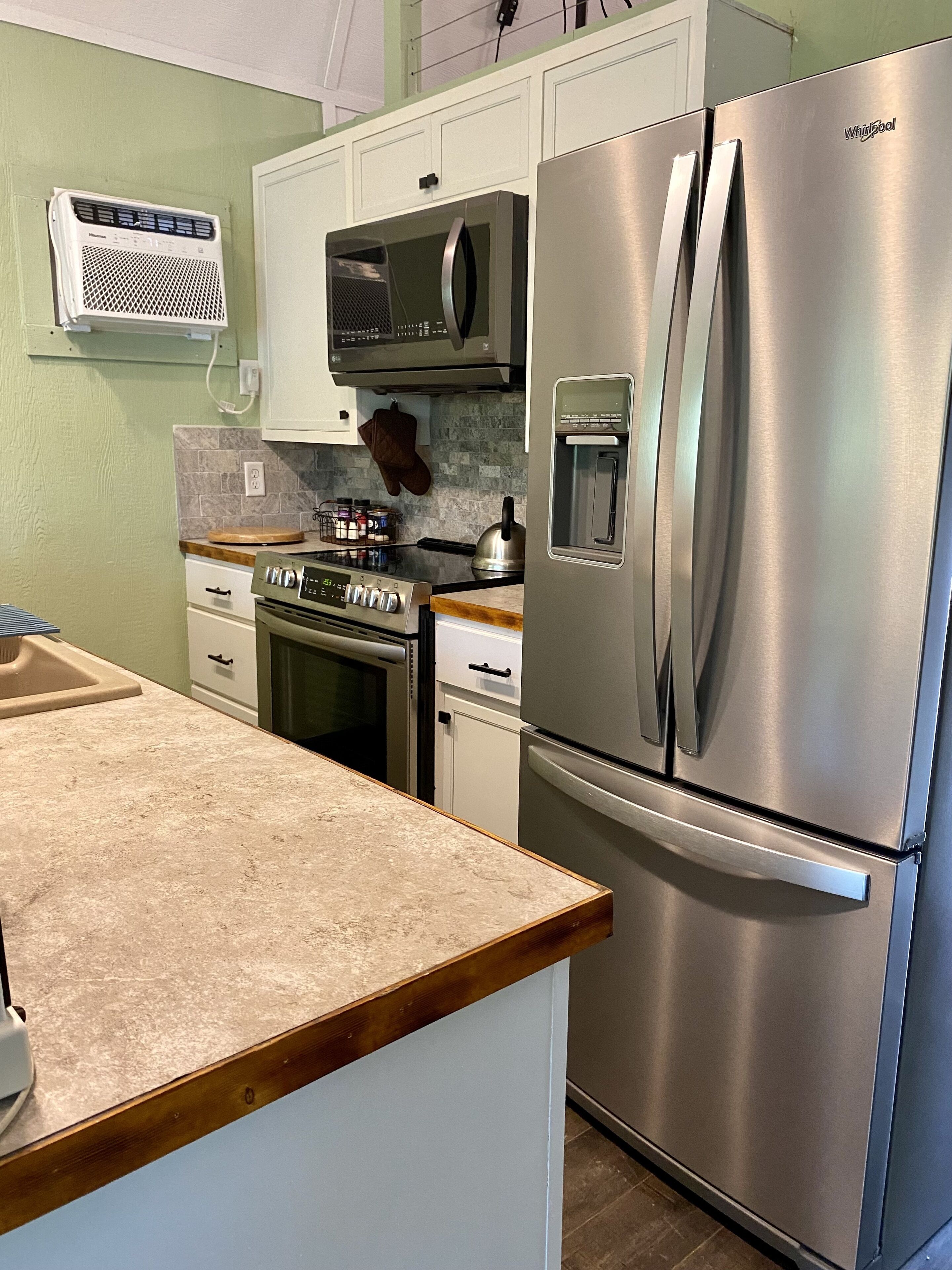 A kitchen with a stainless steel refrigerator, a microwave, an oven, and a water dispenser.