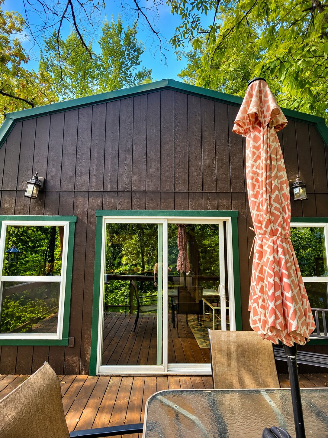 A wooden deck with a glass door leading to a covered patio area.